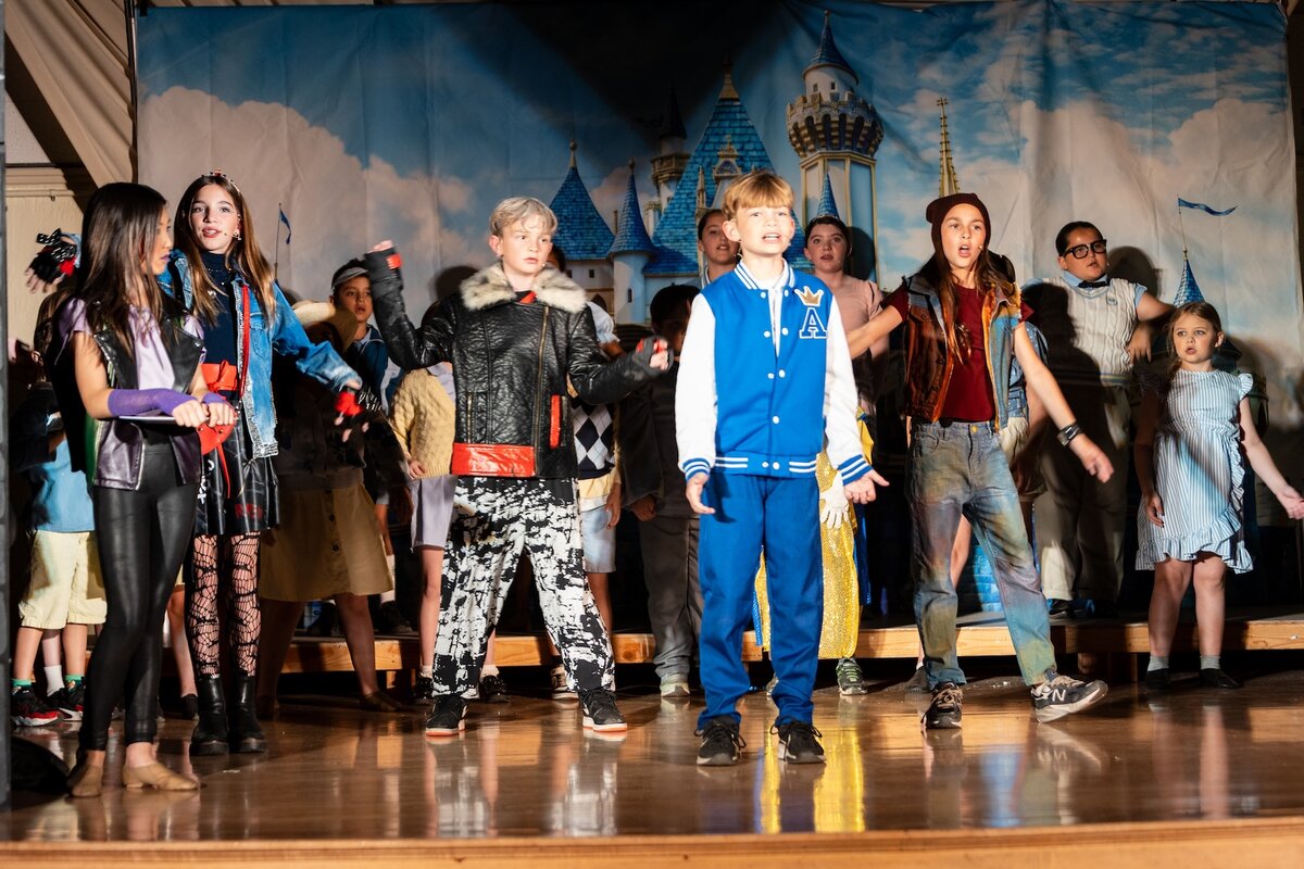 Student cast members singing together on stage during the Descendants production